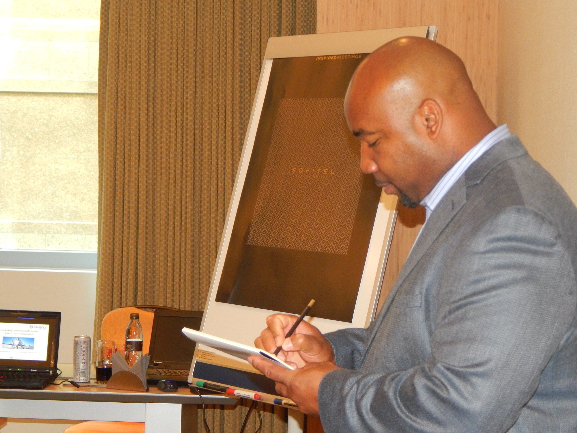 Man writing on notepad during meeting.