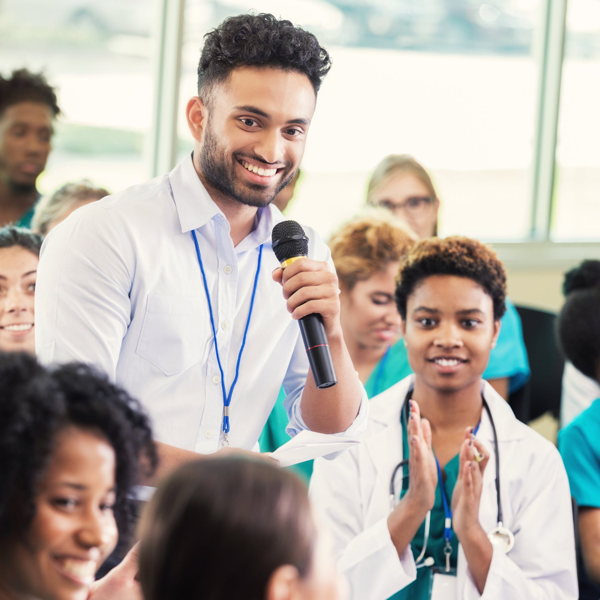 Smiling man with microphone addressing audience.